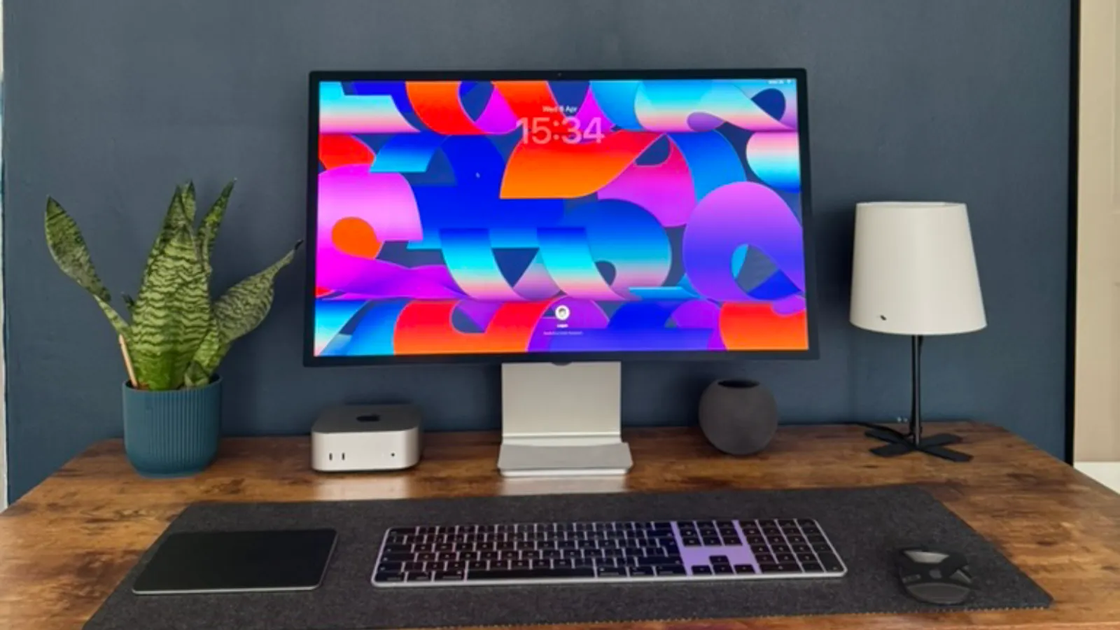 An Apple Studio Display on a desk next to a Mac mini, HomePod mini and Apple Magic Accessories