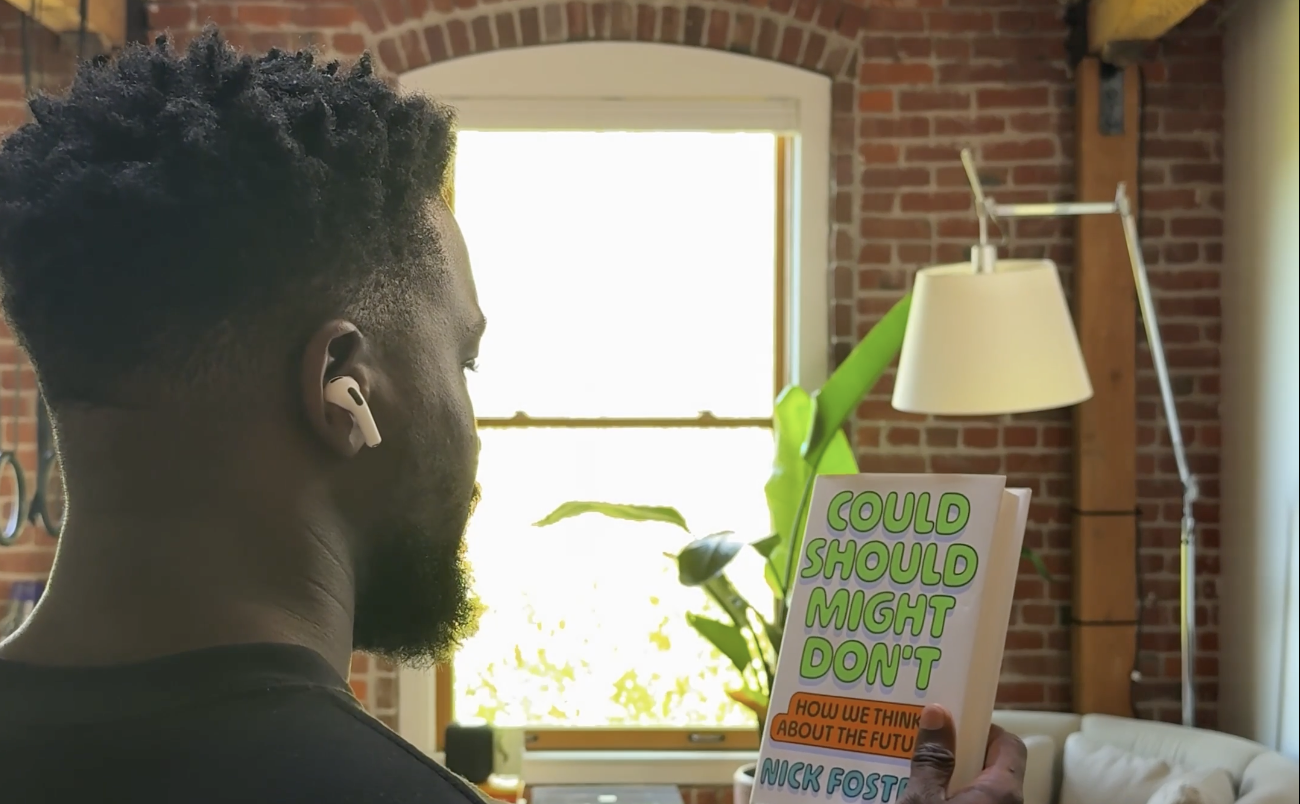 A man wearing AirPods holding a book up to his face
