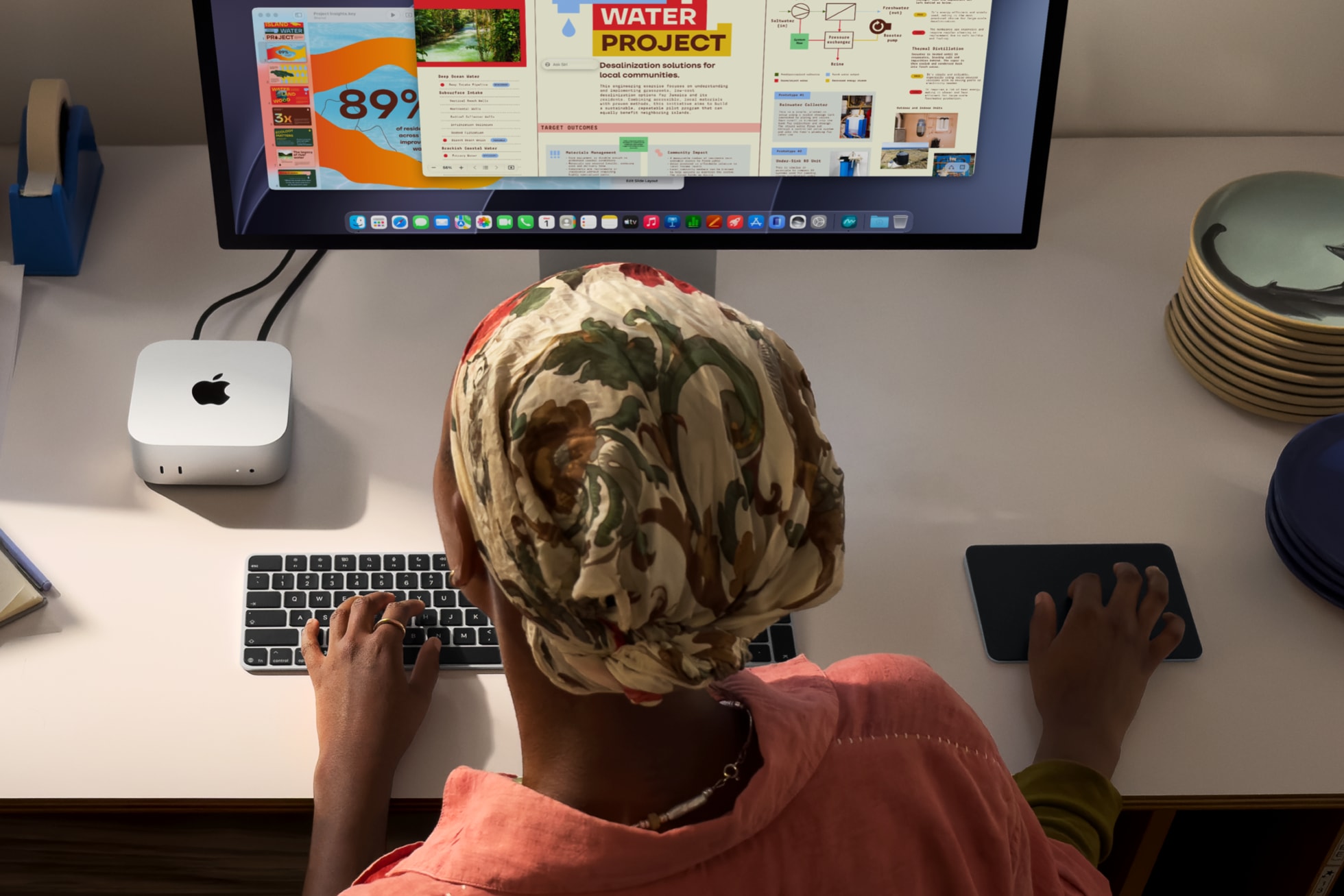 a woman using a mac mini and studio display